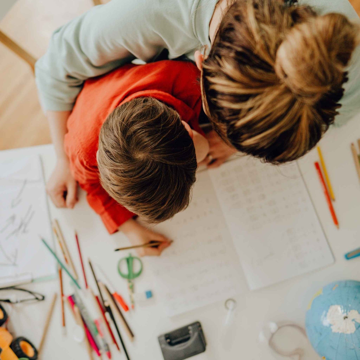 Two children sitting on the floor surrounded by homeshool printable worksheets. Ready Set Homescool