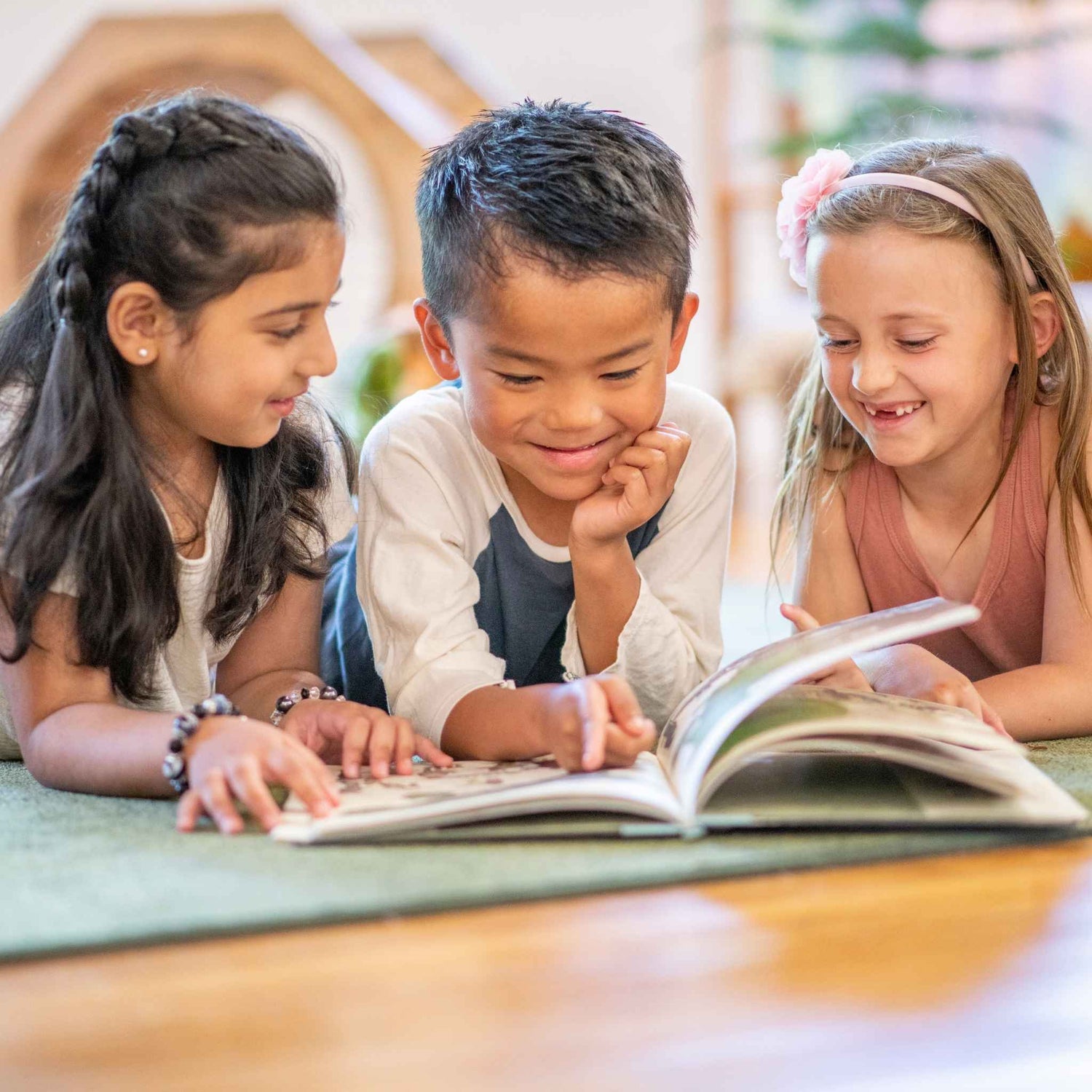 Three children reading a book together in a classroom setting - Rwady Set Homeschool